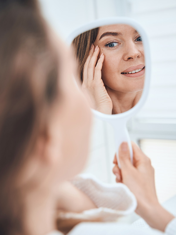 woman looking at a mirror with clear skin